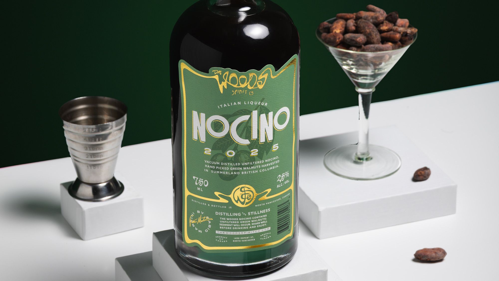 Wood Spirit Co Nocino bottle with walnuts in martini glass and jigger on a green ground