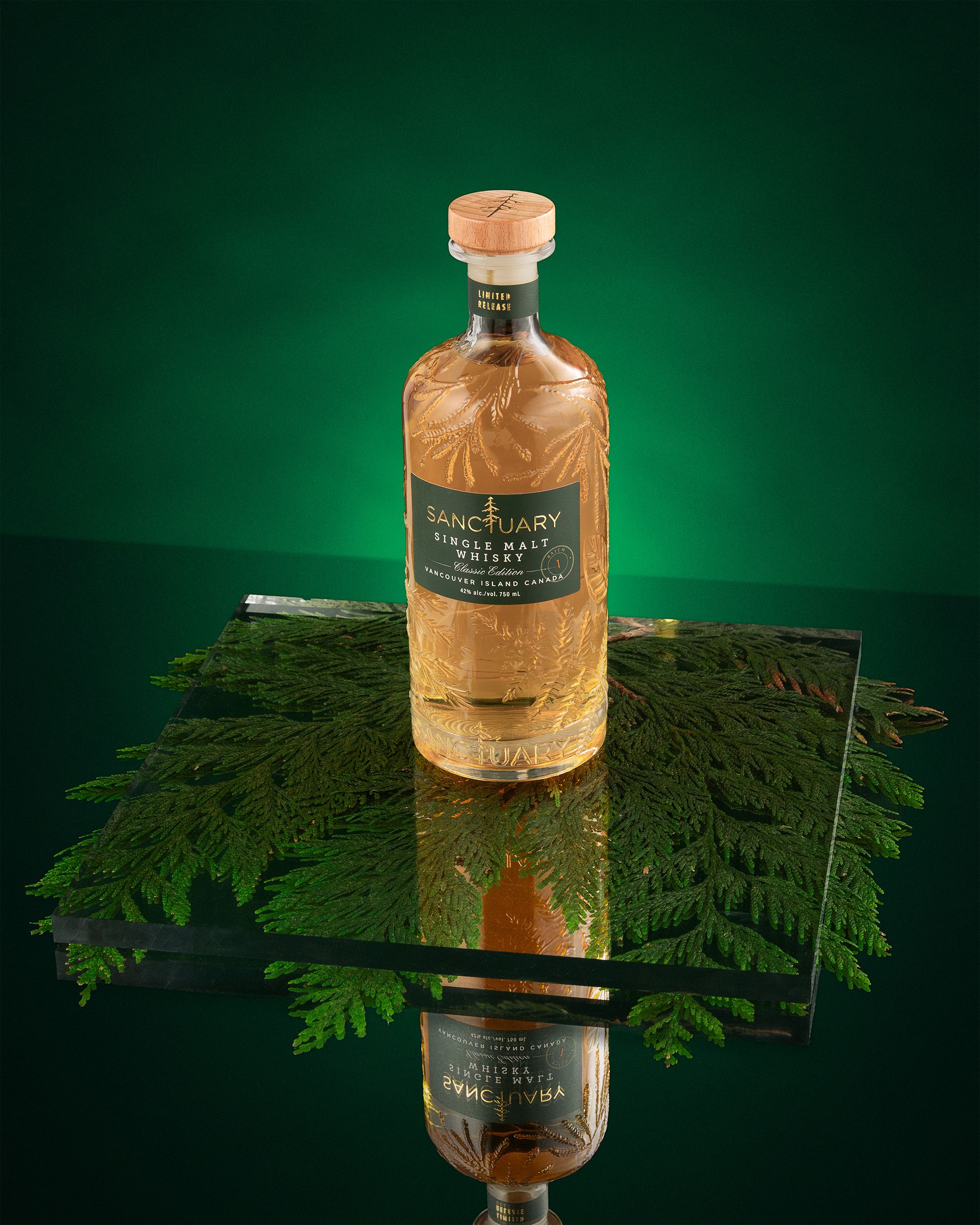 Sanctuary Classic Edition bottle on black glass with cedar, deep green background