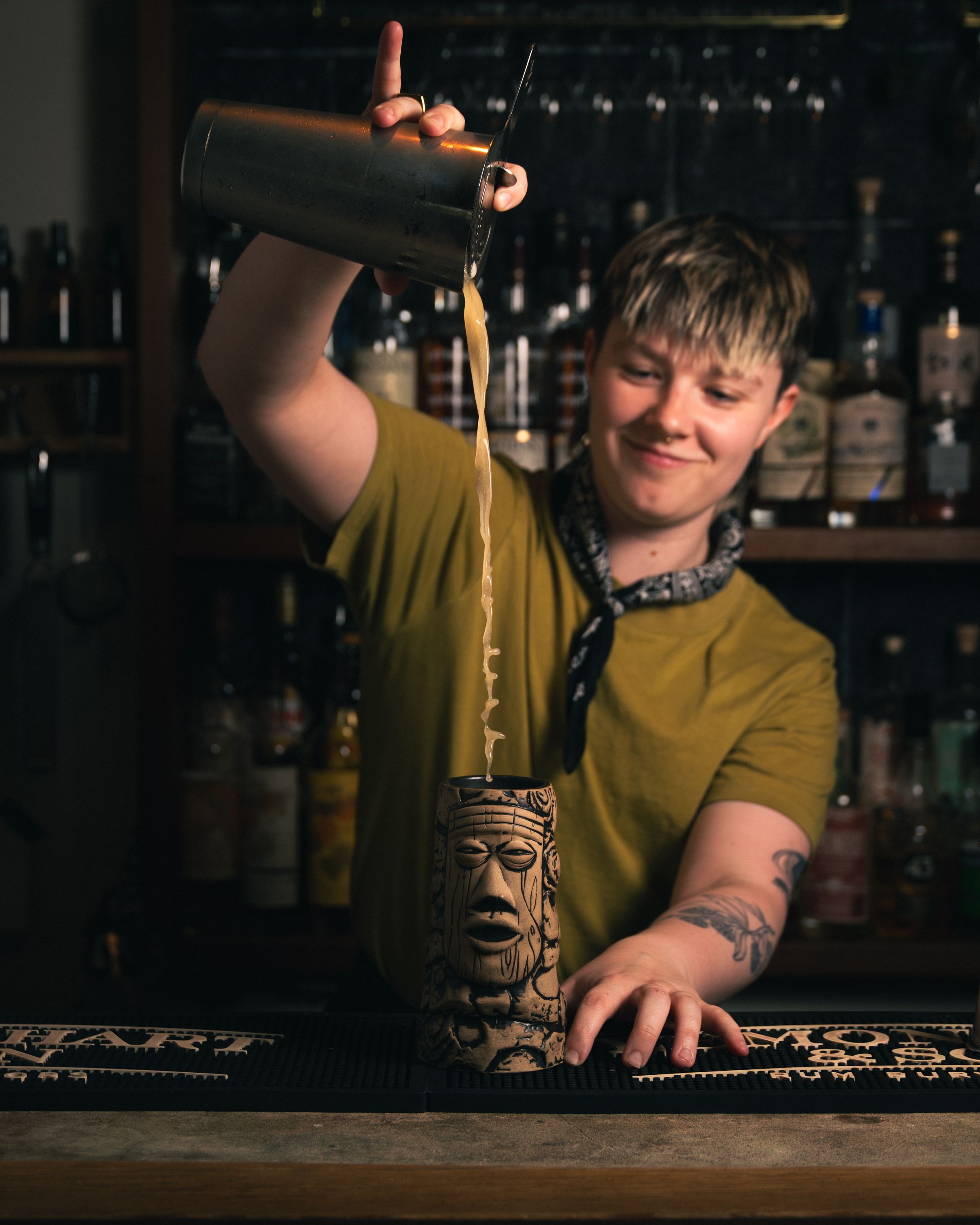 Bartender high-pouring cocktail into a tiki mug at a Sons of Vancouver bar