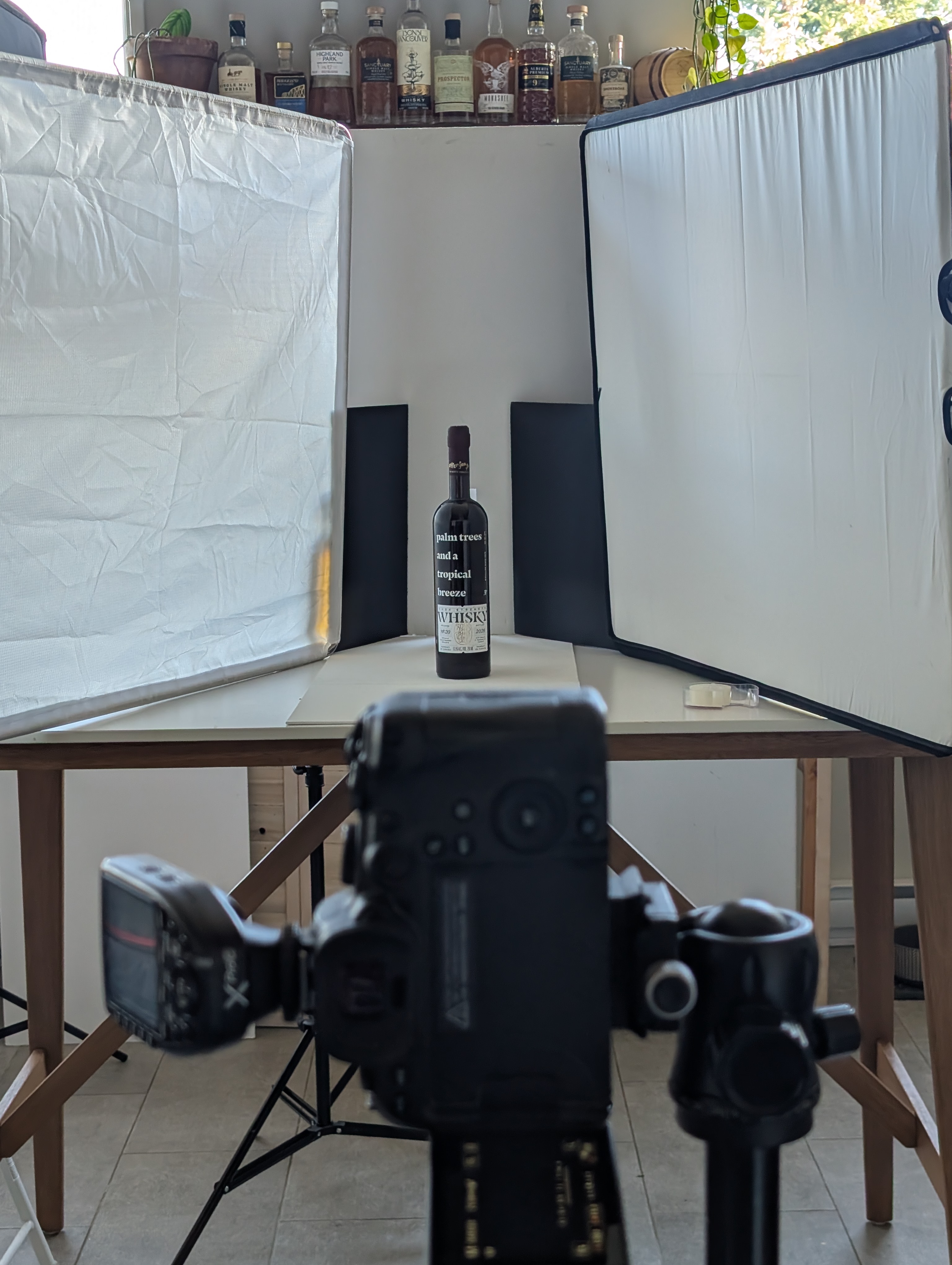 Wide view of the minimal kitchen set, white foam core backdrop and white canvas board base, with the Sons of Vancouver bottle in place