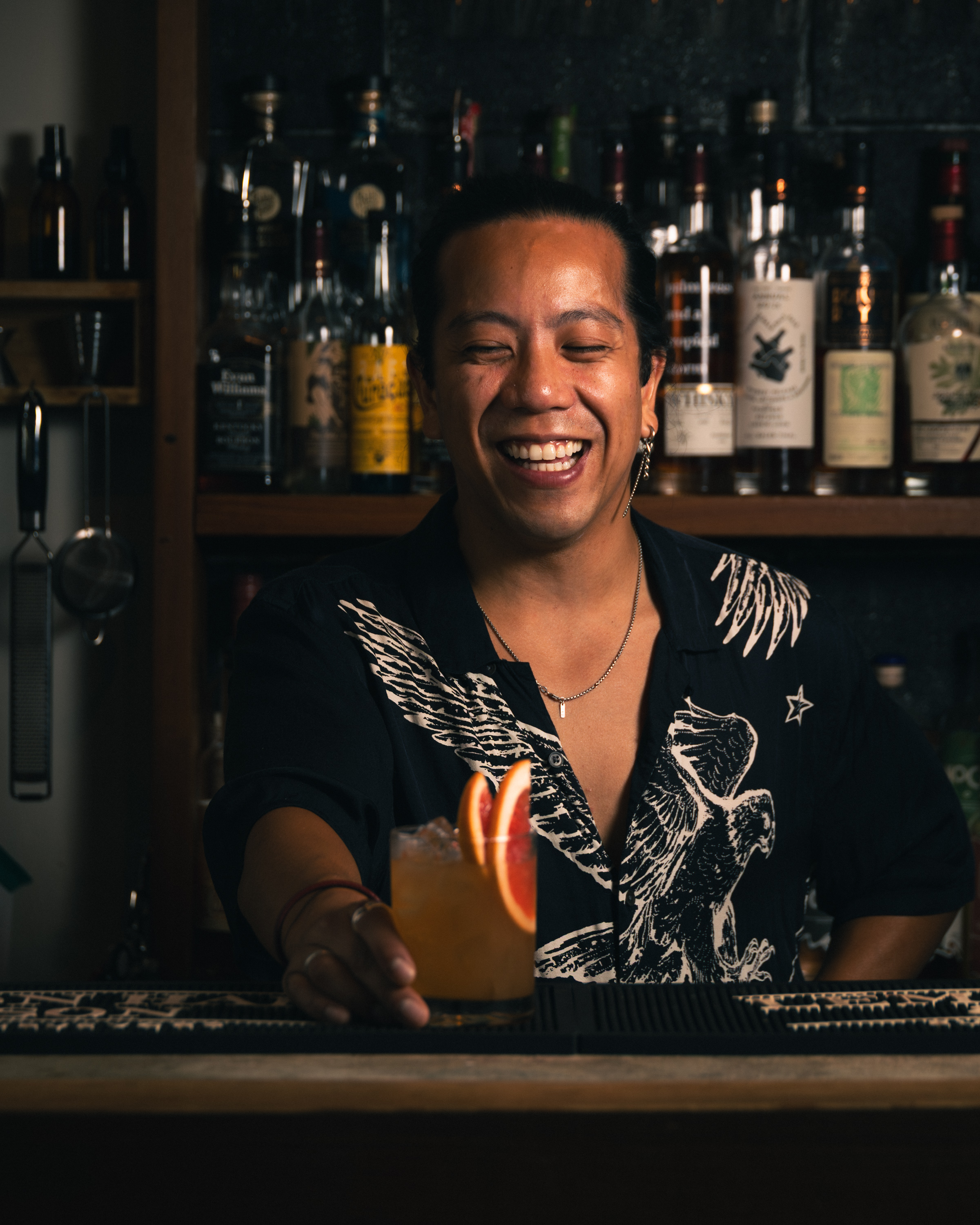 Bartender laughing while presenting a citrus cocktail at a Sons of Vancouver bar event