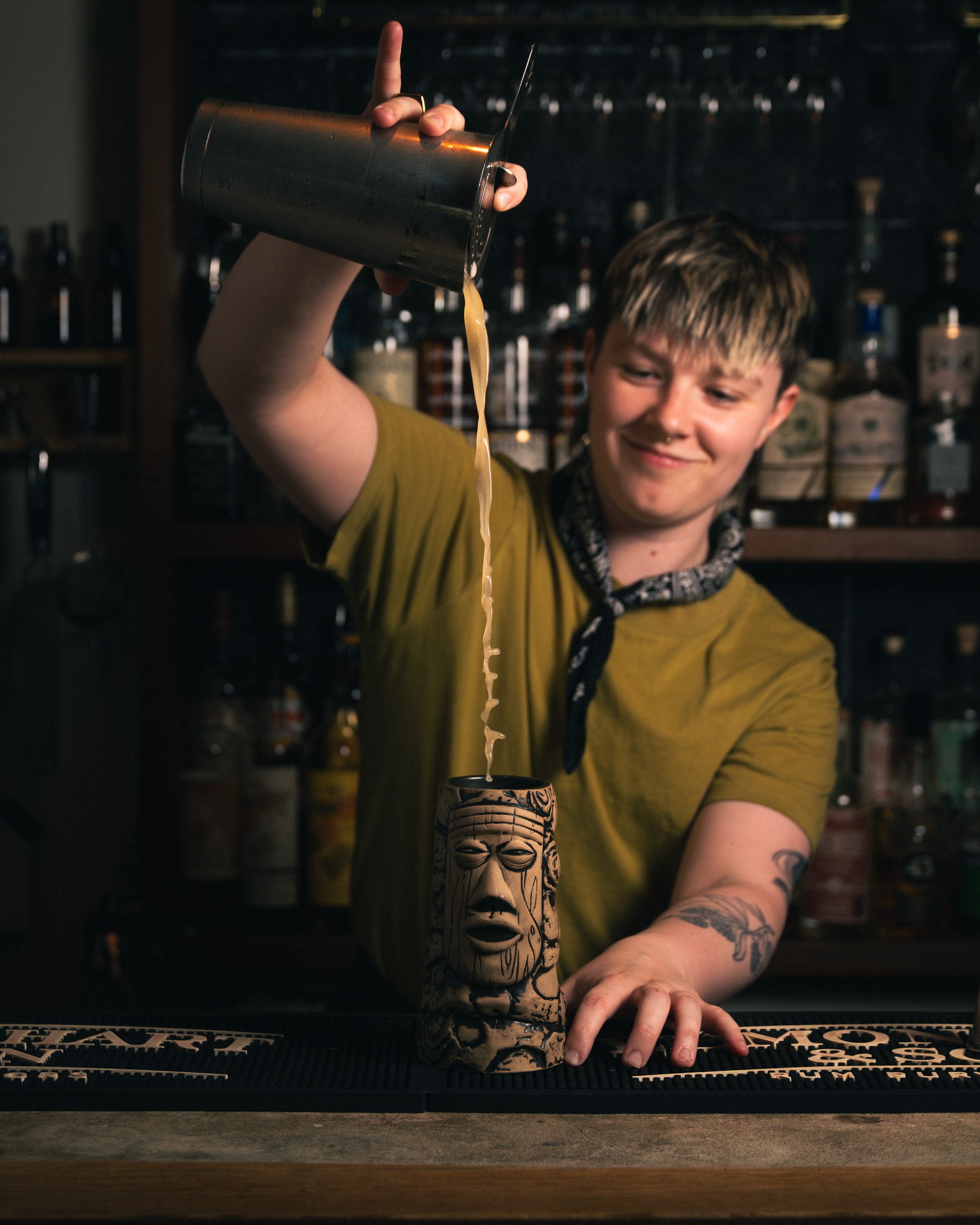 Bartender high-pouring cocktail into a tiki mug at a Sons of Vancouver bar
