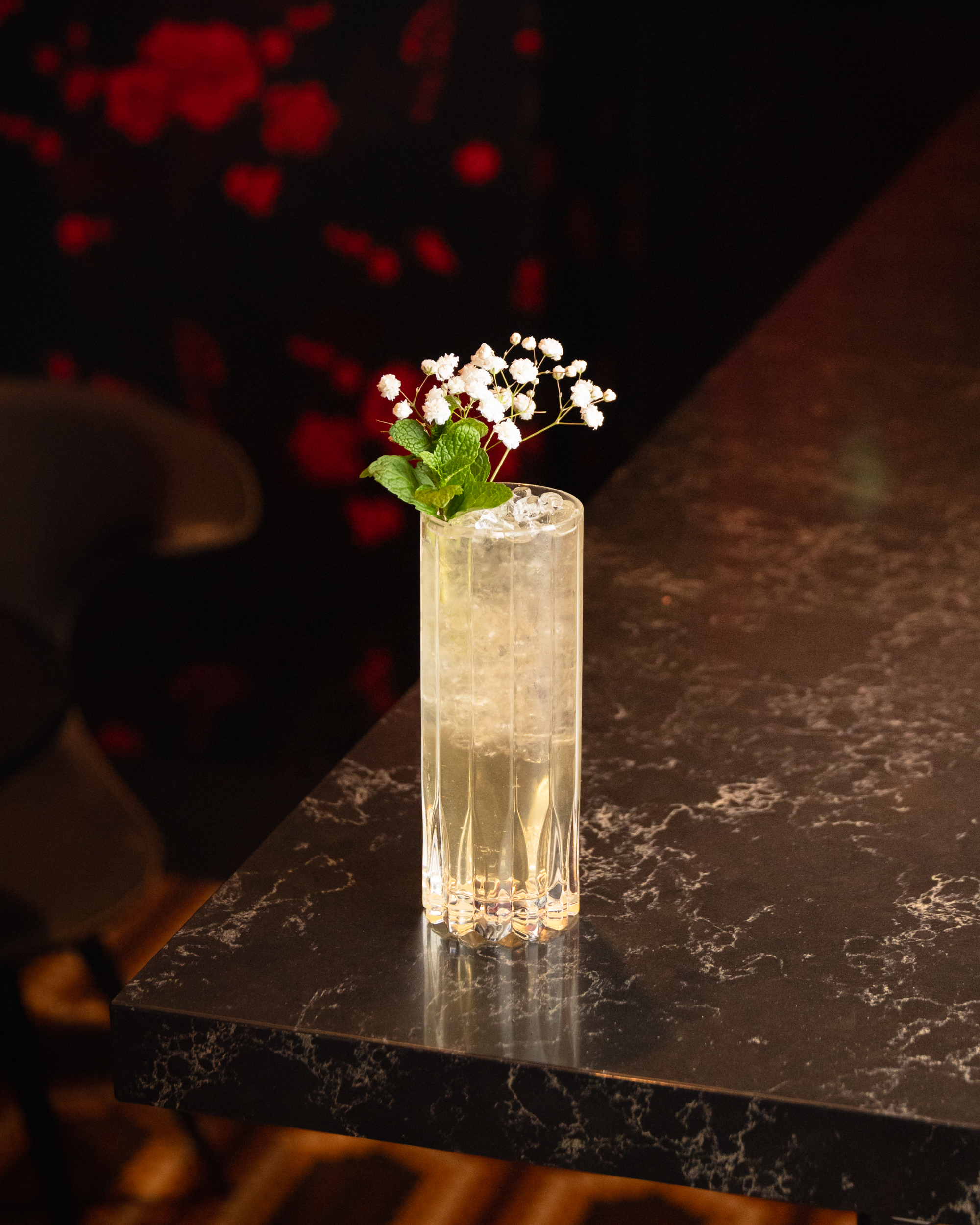 Crystal highball with white flowers and mint garnish on black marble at Terminal City Club
