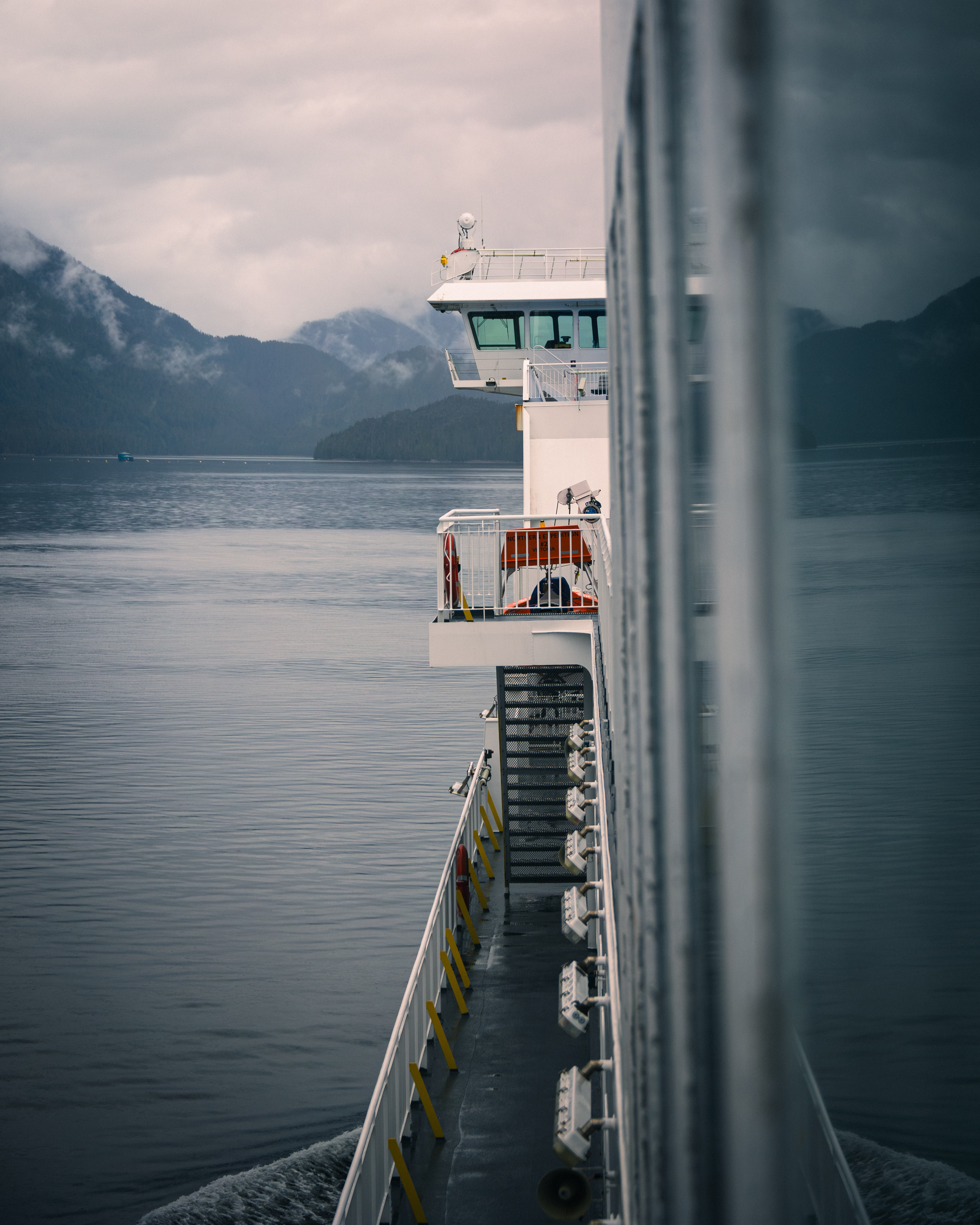 BC ferry deck and superstructure alongside a fjord in overcast light