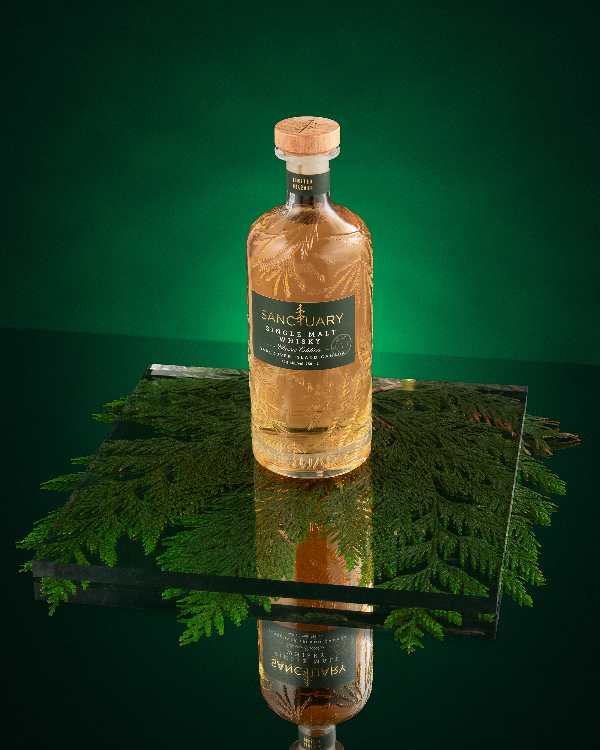 Sanctuary Classic Edition bottle on black glass with cedar, deep green background