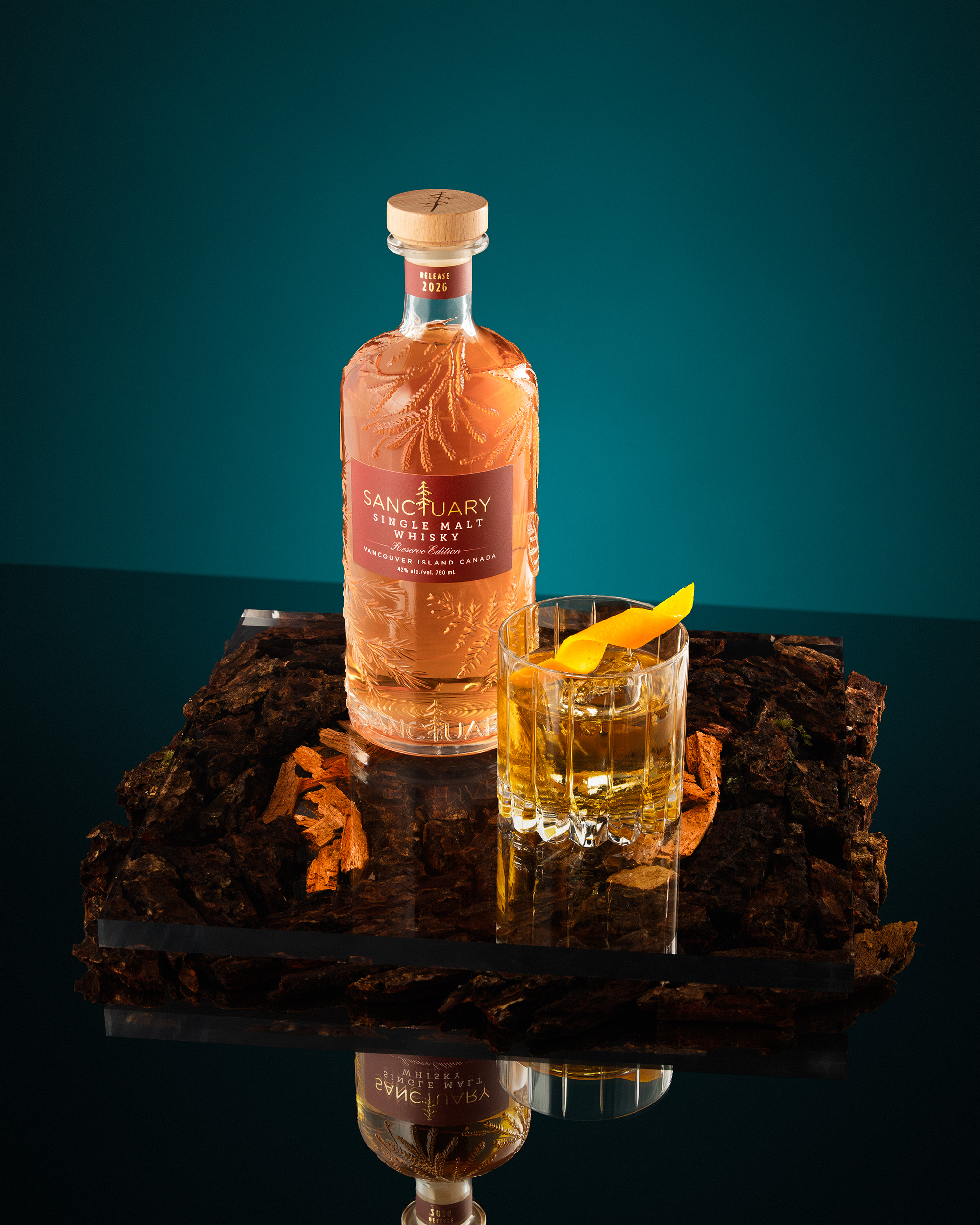 Sanctuary Reserve Edition bottle with old fashioned cocktail on bark, teal background