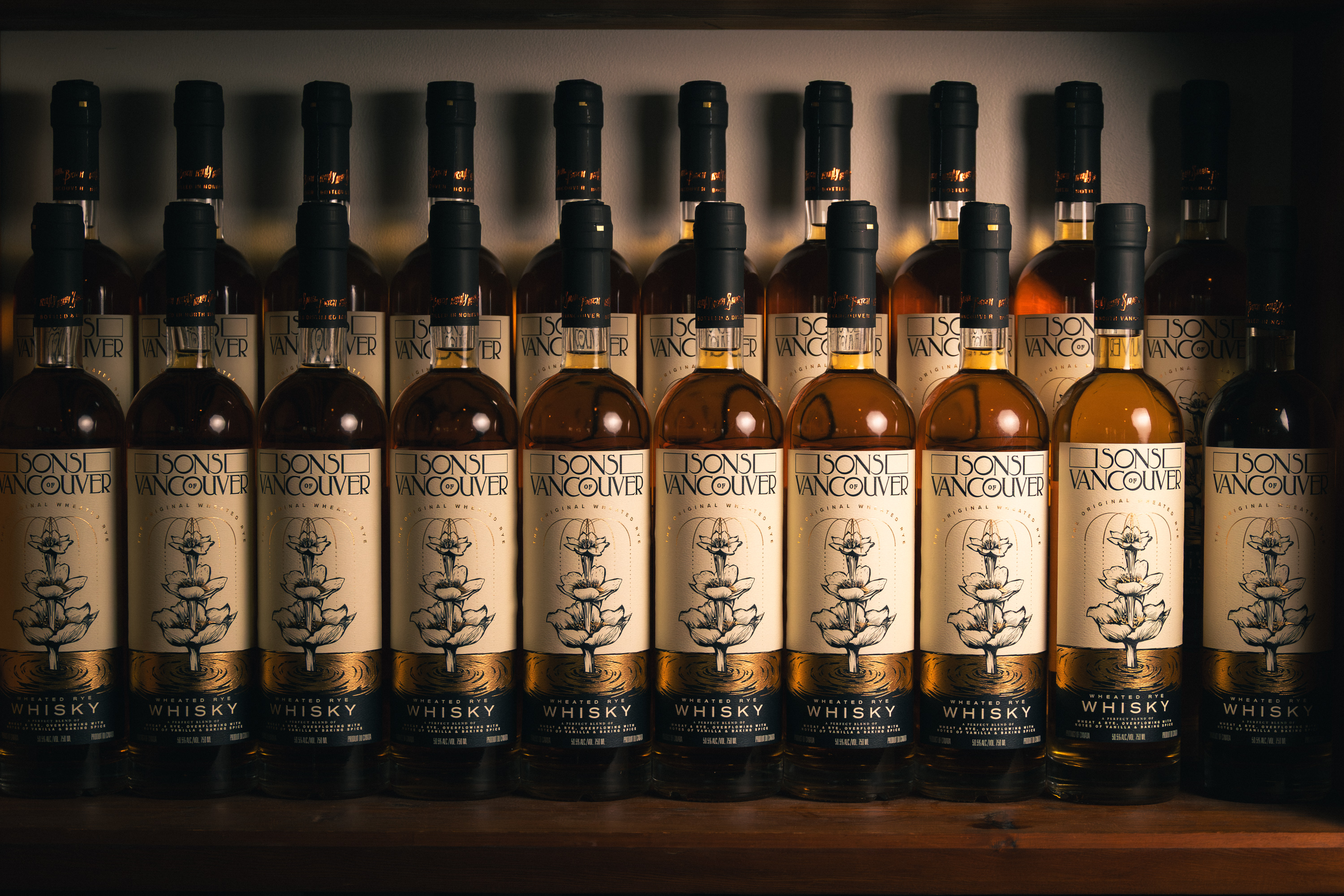 Row of Sons of Vancouver Wheated Rye bottles lined on a dim shelf