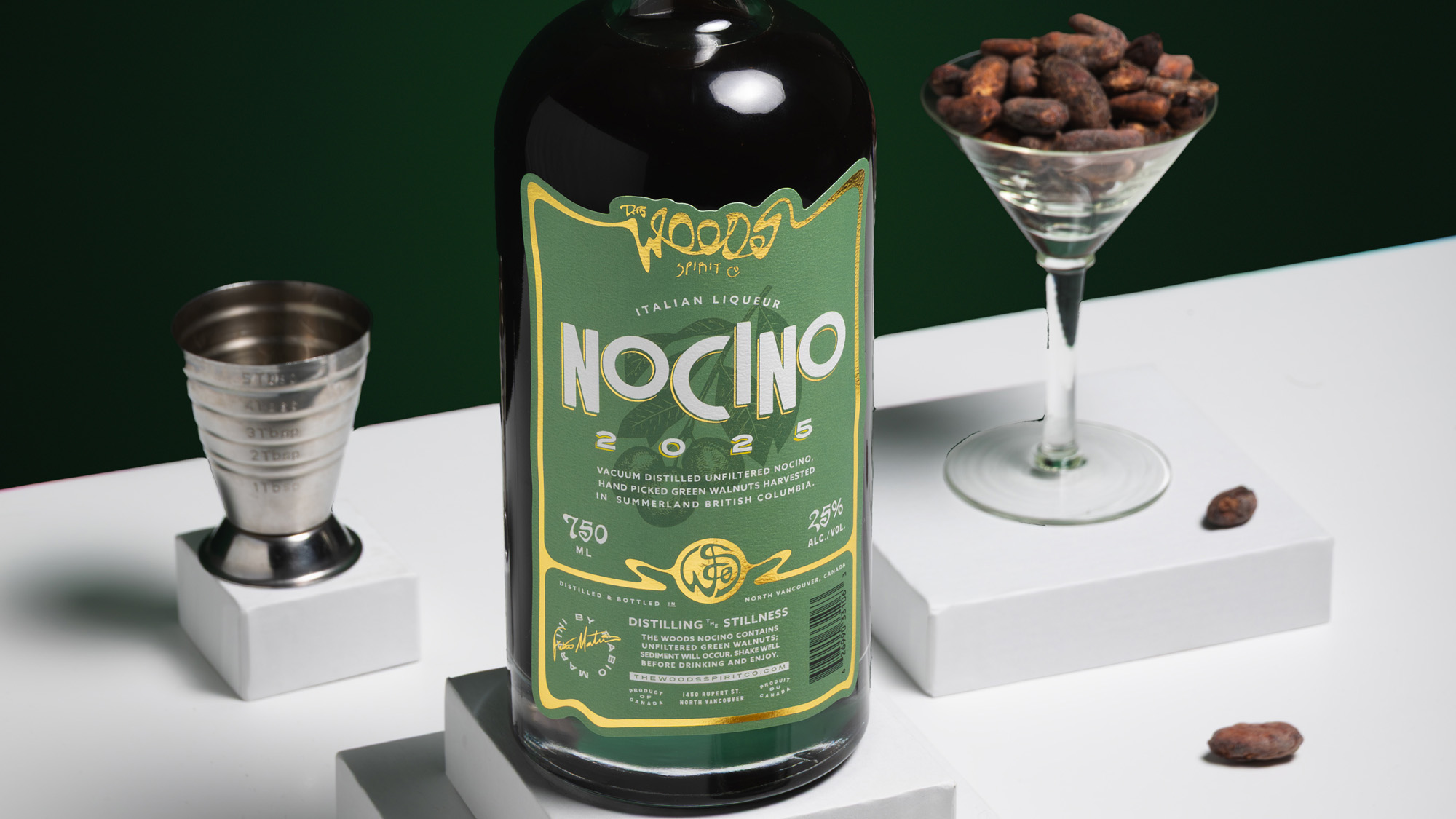 Wood Spirit Co Nocino bottle with walnuts in martini glass and jigger on a green ground